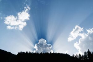 pexels-photo-593227-593227 A stunning natural phenomenon as sunrays pierce through fluffy clouds above a silhouetted forest.